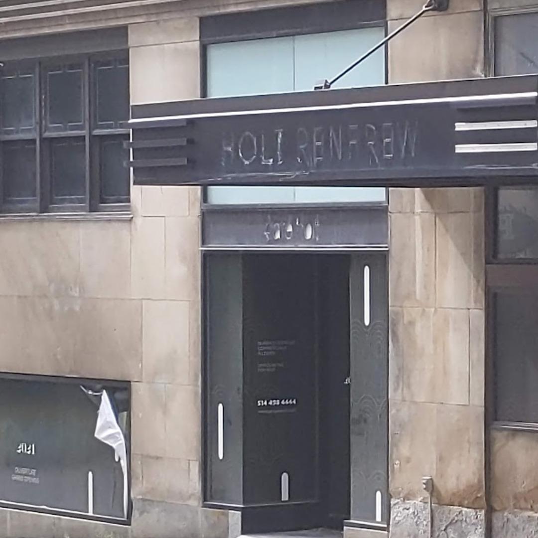 The marquee of the Holt Renfrew store in Montreal.  The letters spelling out the store's name have been removed, and there are signs of other windows being boarded up. 